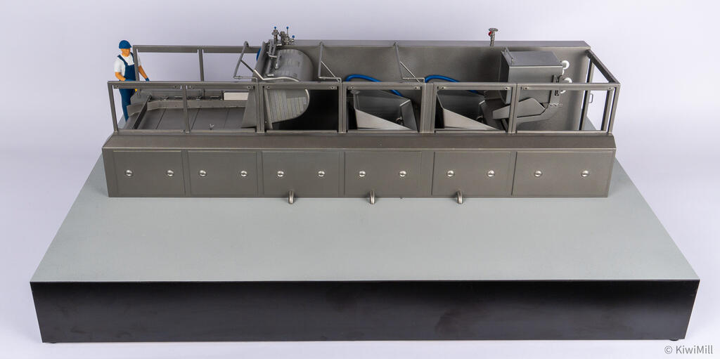 Front view of the cooking line model with grates lifted off, exposing the perforated basket, chutes and tote bin
